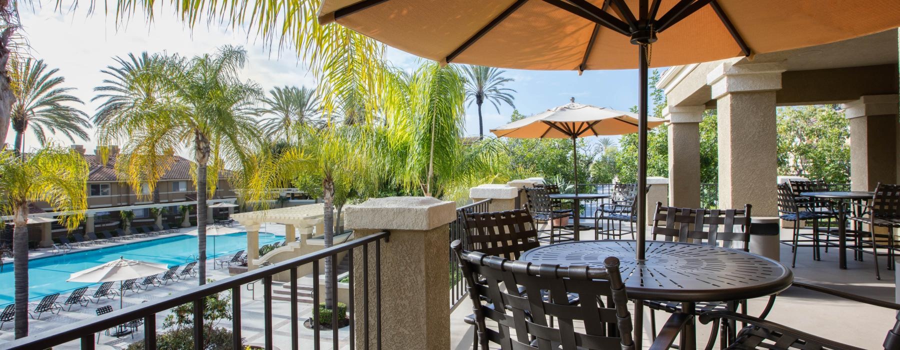 a patio with tables and chairs and umbrellas by a pool